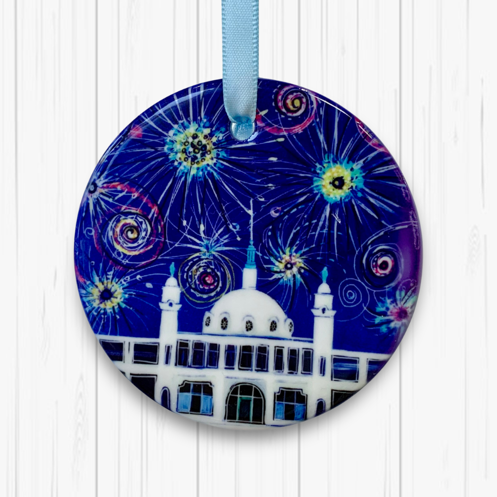 Circular ceramic decoration hung against a white background. It features the Whitley Bay Spanish City Dome under a dark blue sky of colourful fireworks. 